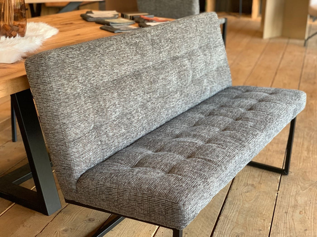 Moderne Sitzbank aus grauem Stoff mit gesteppter Sitzfläche und gepolsterter Rückenlehne, Detailansicht neben einem Holztisch im Essbereich