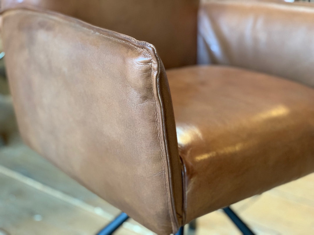 Detailaufnahme eines drehbaren Polsterstuhls aus hochwertigem Leder in Braun, mit feiner Nahtführung und edler Oberfläche – stilvoll präsentiert im Showroom in Hamburg.