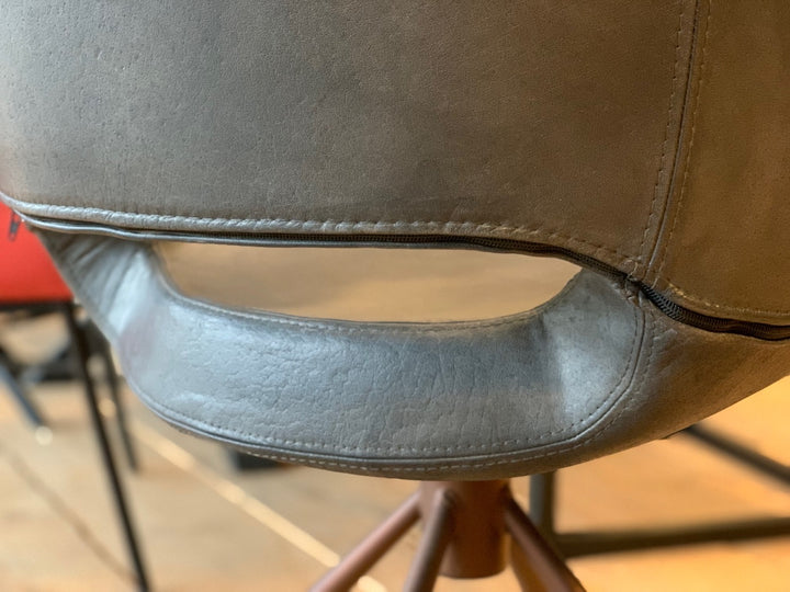 Detailaufnahme eines Schalenstuhl drehbar Leder mit grauer Lederoberfläche, sichtbaren Nähten und charakteristischer Öffnung im Rückenbereich, die die hochwertige Verarbeitung und Polsterung des Stuhls hervorhebt.
