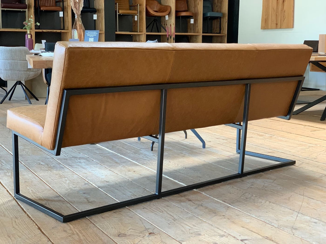 Rückansicht einer modernen Esszimmerbank mit braunem Lederbezug und stabilem schwarzen Metallgestell im stilvollen Möbel-Showroom