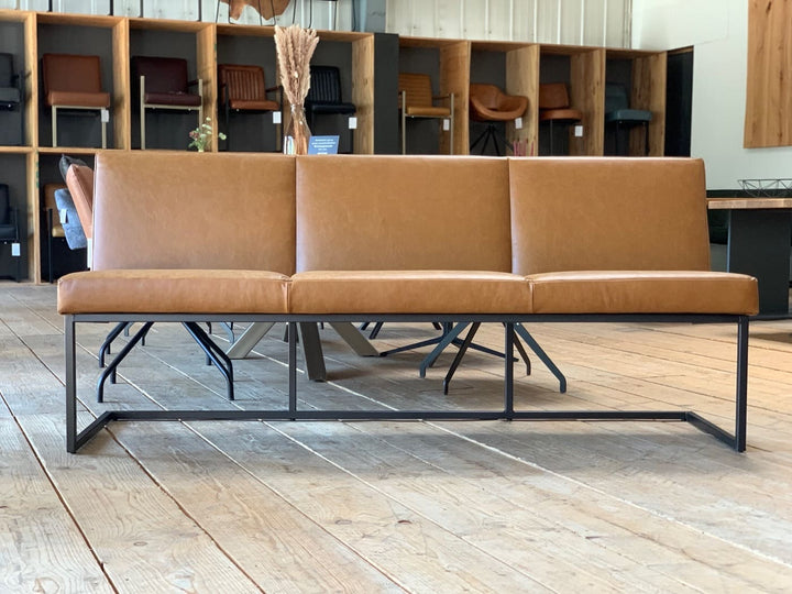Moderne Esszimmerbank mit braunem Lederbezug und schwarzem Metallgestell in einem stilvollen Möbel-Showroom auf Holzboden