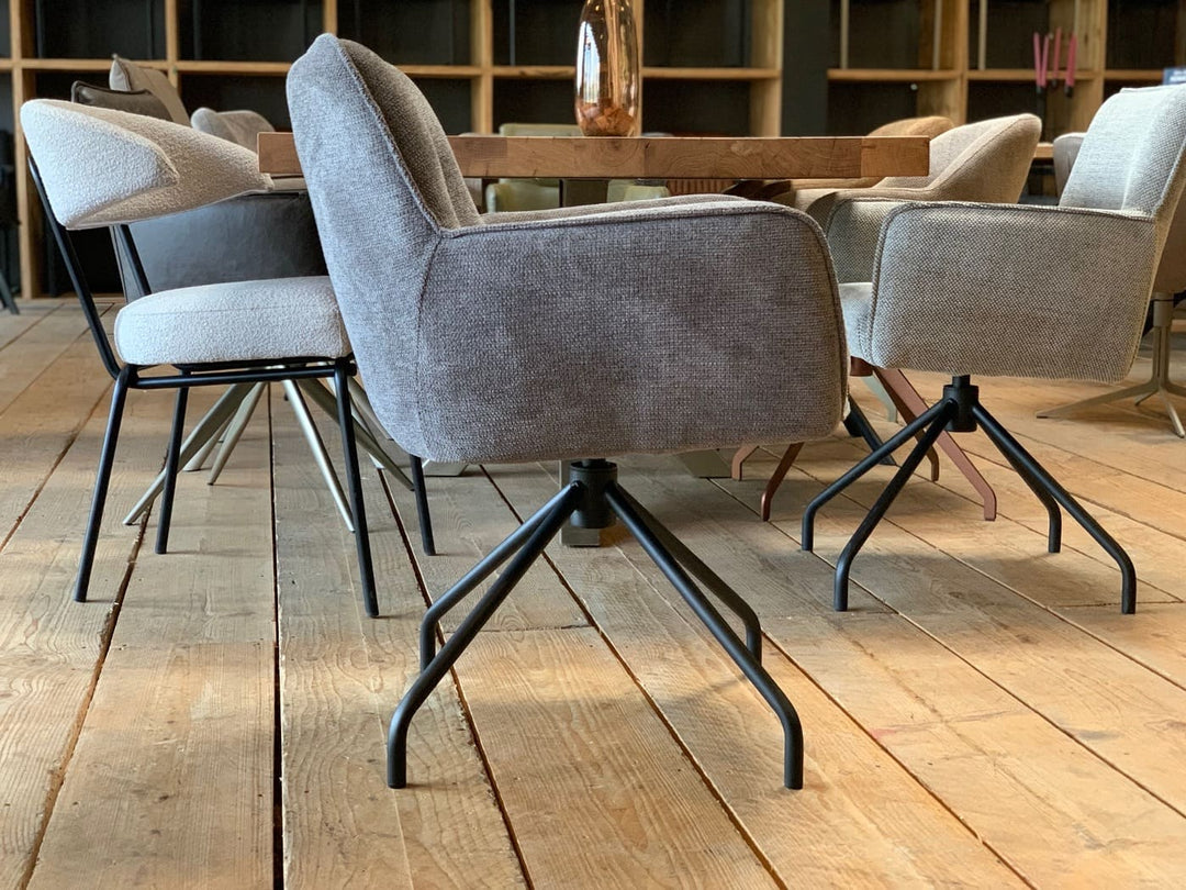 Drehbarer Stoffstuhl in Seitenansicht mit gepolsterter Sitzschale, grauem Stoffbezug und schwarzem Metallgestell im modernen Esszimmer.