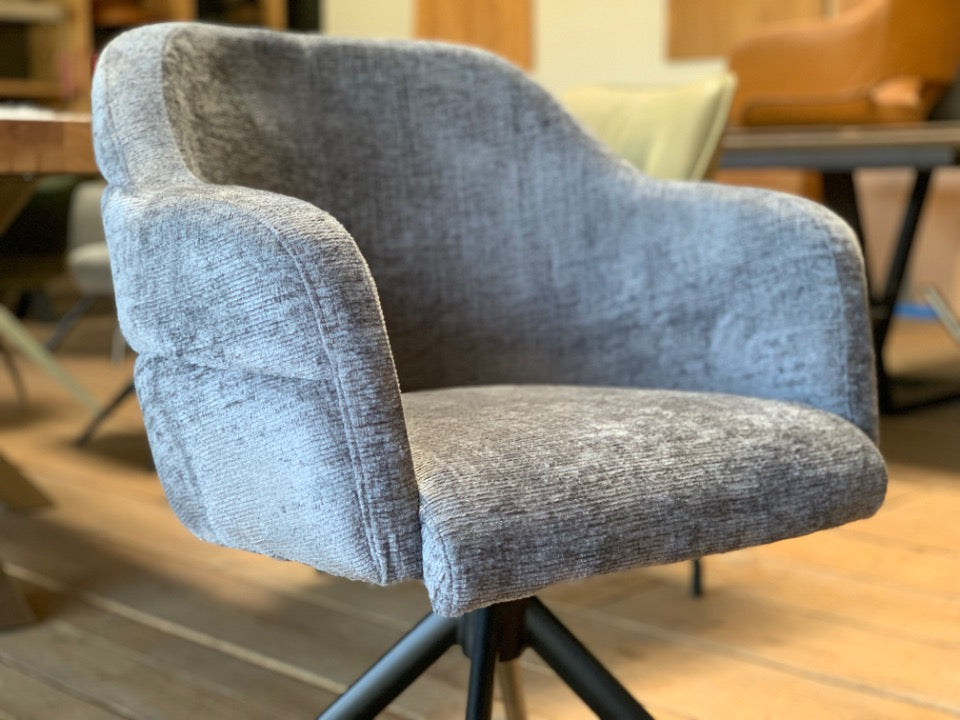 Detailaufnahme der gepolsterten Sitzschale eines modernen Stoffstuhls mit Drehfunktion – weicher, strukturierter Bezug, ergonomisch geformte Armlehnen und hoher Sitzkomfort für stilvolle Essbereiche.