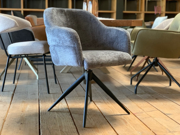 Moderner Stoffstuhl mit Drehfunktion und gepolsterter Sitzschale in Grau, kombiniert mit einem schwarzen Metallgestell in Sternform – ideal für stilvolle Essbereiche.
