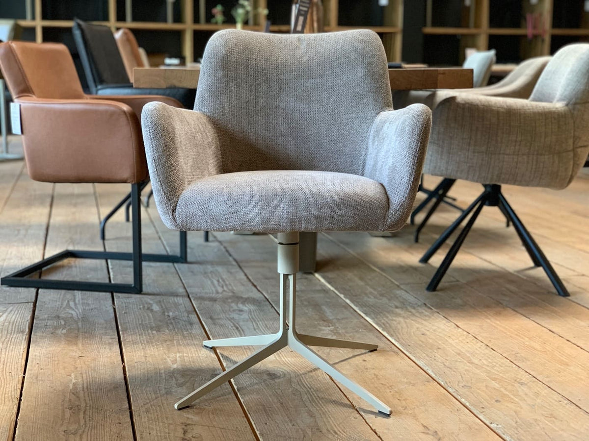 Stühle Esszimmer in Stoff in Vorderansicht mit grauem Bezug, gepolsterter Sitzschale und Armlehnen, drehbar auf hellem Stahlgestell mit sternförmigem Fuß, in modernem Essbereich mit Holztisch und weiteren Sitzmöbeln im Hintergrund.