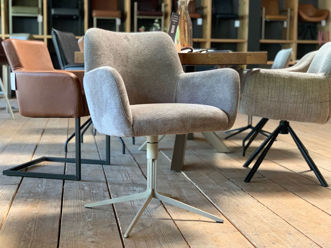 Stühle Esszimmer in Stoff mit grauem Bezug, gepolsterter Sitzschale und Armlehnen, drehbar auf hellem Stahlgestell mit sternförmigem Fuß, in modernem Essbereich mit Holztisch und weiteren Sitzmöbeln im Hintergrund.