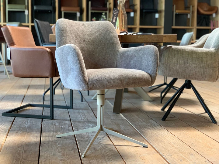 Stühle Esszimmer in Stoff mit grauem Bezug, gepolsterter Sitzschale und Armlehnen, drehbar auf hellem Stahlgestell mit sternförmigem Fuß, in modernem Essbereich mit Holztisch und weiteren Sitzmöbeln im Hintergrund.