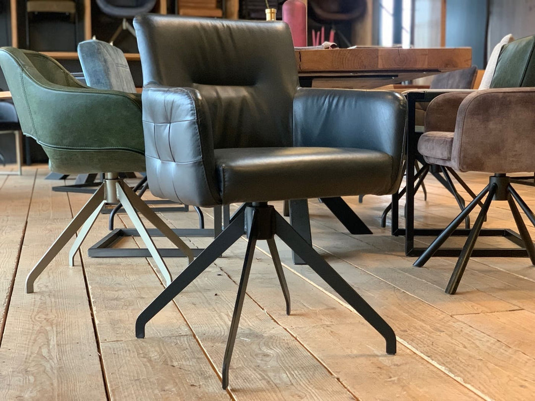 Vorderansicht eines Stuhl Esszimmer Leder drehbar in schwarzer Lederfarbe mit gepolsterten Armlehnen und robuster Sitzfläche, auf einem stabilen Metallgestell, platziert an einem Holztisch in einem modernen Essbereich mit weiteren Stühlen im Hintergrund.