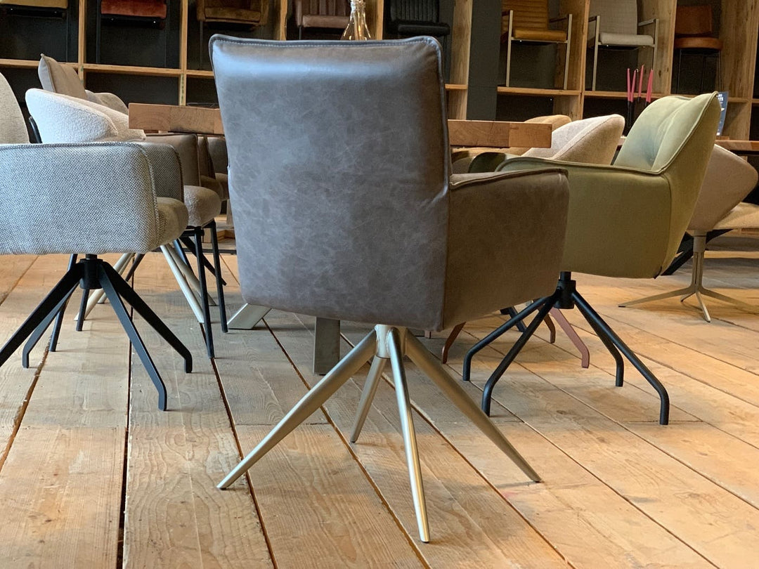 Rückansicht eines modernen Stuhl Esszimmer Leder drehbar 158T mit hochwertiger Lederpolsterung, geradliniger Rückenlehne und sauberer Nahtführung, ausgestattet mit einem stabilen drehbaren Metallgestell in eleganter Sternform; platziert an einem Esstisch in einem stilvollen Essbereich mit weiteren Stühlen im Hintergrund.