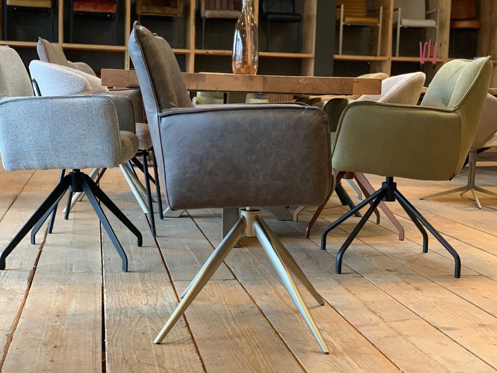 Seitliche Ansicht eines eleganten Stuhl Esszimmer Leder drehbar 158T mit hochwertiger Lederpolsterung, klarer Linienführung, gepolsterten Armlehnen und stabiler Rückenlehne, kombiniert mit einem drehbaren Metallgestell in moderner Sternform; platziert an einem Esstisch in einem stilvollen Essbereich mit weiteren Stühlen im Hintergrund.