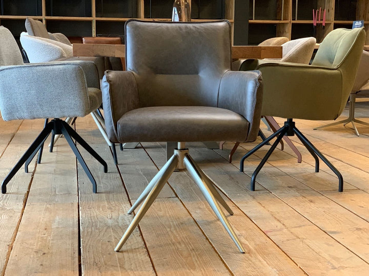 Frontansicht eines eleganten Stuhl Esszimmer Leder drehbar 158T mit hochwertiger Lederpolsterung, komfortabler Sitzfläche, gerader Rückenlehne und gepolsterten Armlehnen, kombiniert mit einem stabilen drehbaren Metallgestell in moderner Sternform; platziert an einem Esstisch in einem stilvollen Essbereich mit weiteren Stühlen im Hintergrund.