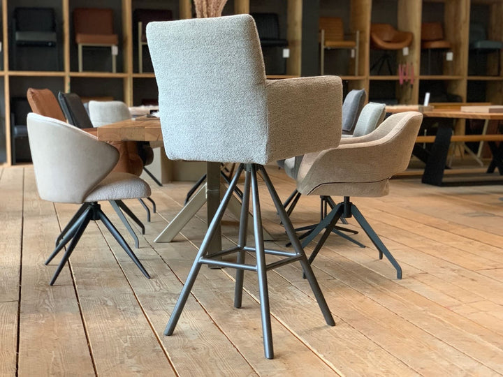 Drehbarer Thekenstuhl aus Stoff in Rückansicht mit hoher gepolsterter Rückenlehne und Armlehnen auf schwarzem Metall-Drehgestell in modernem Möbelshowroom.